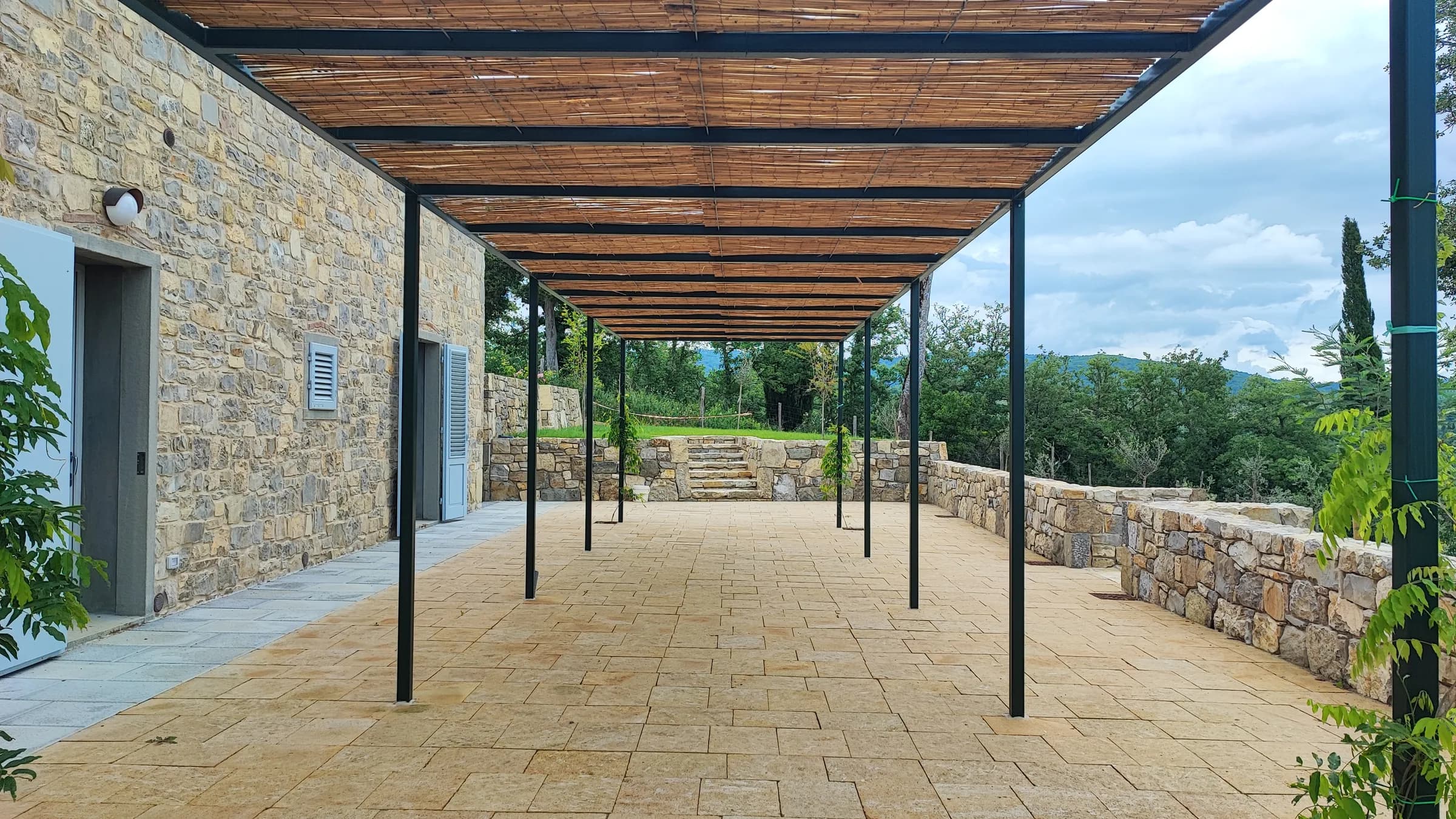 Terrazzo pavimentato con pergola in ferro e vista sulle colline